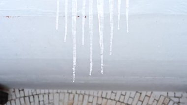 Konut binasının girişinde büyük buz saçakları var. Binanın girişine buz saçakları asmak, hayatı tehlikeye atar. Keskin buz sarkıtları eski bir apartmanın çatısında asılı..