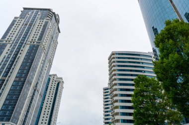 Grozny, Çeçenistan, Rusya - 30 Haziran 2024: Grozny City 'nin gökdelenleri. Mavi, bulutlu gökyüzüne karşı geniş, pencerelerle kaplı bir binanın açılı görüntüsü..