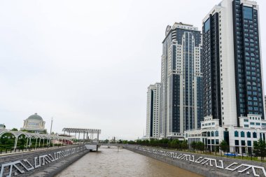 Grozny, Çeçenistan, Rusya - 30 Haziran 2024: Grozny City 'nin gökdelenleri. Mavi, bulutlu gökyüzüne karşı geniş, pencerelerle kaplı bir binanın açılı görüntüsü..