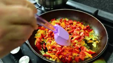 Biberler, domatesler, soğanlar ve rendelenmiş havuçlar kızarırken tavada cızırdar, aromaları mutfağı doldurur. Bir spatula karışımı karıştırır, hatta yemek pişirmesini sağlar ve lezzetlidir..