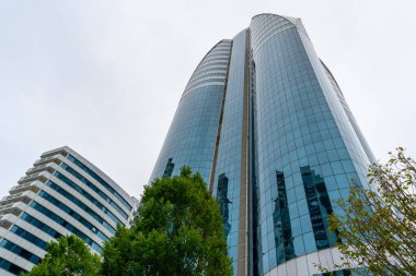 Grozny, Çeçenistan, Rusya - 30 Haziran 2024: Grozny City 'nin gökdelenleri. Mavi, bulutlu gökyüzüne karşı geniş, pencerelerle kaplı bir binanın açılı görüntüsü..