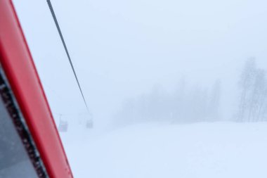 Yoğun sisle kaplı karlı bir ormanda teleferik hattı. Bir gizem ve sakinlik atmosferi.