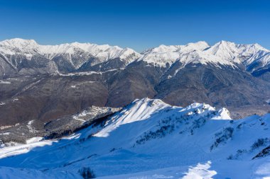 Mountainside, vadi. Arka planda güzel karlı dağlar ve vadi manzarası var. Parlak kış güneşi kar beyazı manzaraları vurgular.