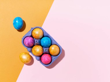 Parlak arkaplanda renkli paskalya yumurtaları olan üst görüntü düzeni. Festival içeriği için yaratıcı şablon