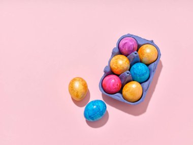 Pembe arka planda renkli paskalya yumurtaları olan üst görüntü düzeni. Festival içeriği için yaratıcı şablon