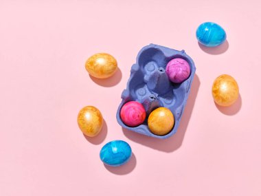 Pembe arka planda renkli paskalya yumurtaları olan üst görüntü düzeni. Festival içeriği için yaratıcı şablon