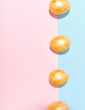 Parlak mavi ve pembe arka planda renkli altın paskalya yumurtaları olan yaratıcı bir düzen. Şenlikli betimleme kavramı