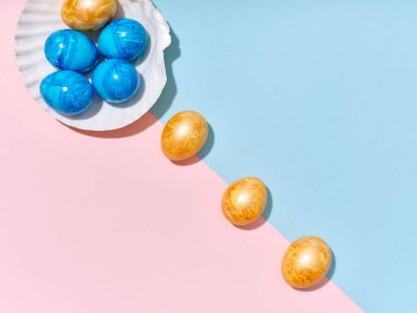 Renkli paskalya yumurtalarıyla birlikte parlak mavi ve pembe arka planda deniz kabuğu şeklinde tasarlanmış yaratıcı bir düzen. Festival içeriği için bir şablon