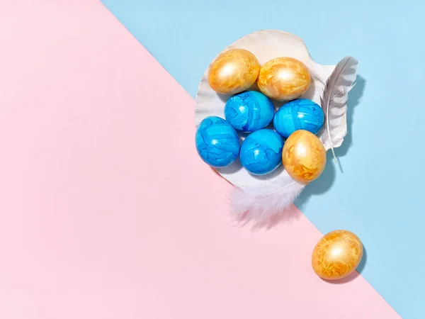 明るい青とピンクの背景に貝殻の中に配置された色のイースターエッグと創造的なレイアウト お祝い事用テンプレート — ストック写真