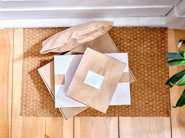 Stack of delivered cardboard parcels on a door mat next to apartment entrance
