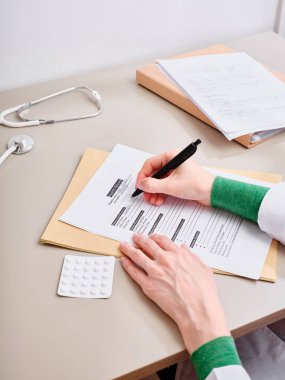 Üst düzey doktor klinikteki tıbbi belgelere not alıyor.