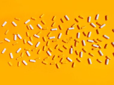 Sarı arka planda çeşitli gıda takviye hapları.