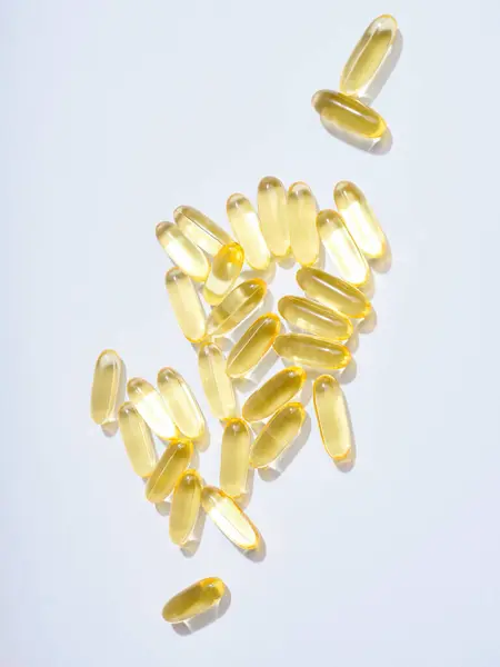 Omega Píldoras Translúcidas Doradas Sobre Fondo Plano Fotos de stock