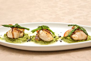 Akdeniz mürekkepbalığı yumurtası aperatifi. Beyaz tabakta kuşkonmaz.