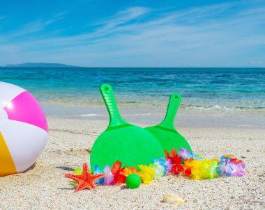 Yazın deniz kenarında kumsalda top ve raket.