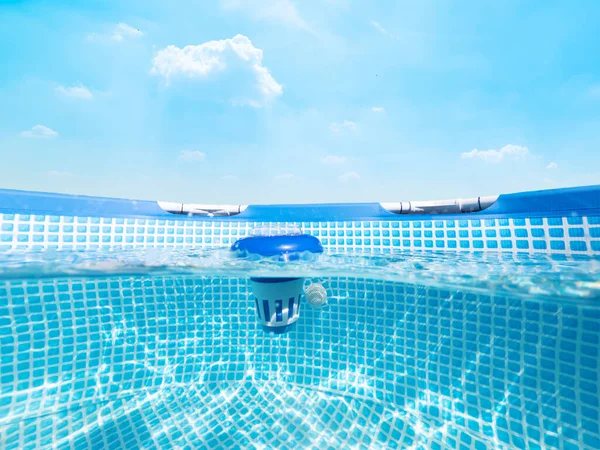 青い空の下のプールで塩素製のフローターディスペンサーの水中ビューを分割 ストックフォト