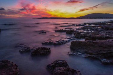 Gün batımında Alghero 'nun üzerinde pembe bir gökyüzü. Sardunya, İtalya