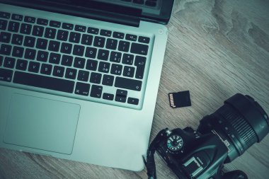 Dizüstü bilgisayar, fotoğraf makinesi ve SD kartı yukarıdan görünüyor