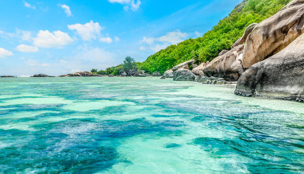 Granite rocks and coral reef in world famous Anse Source d'Argent beach. La Digue, Seychelles