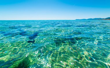 Piscina Rei sahilinde turkuaz su ve mavi gökyüzü. Sardunya, İtalya