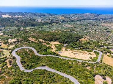 Arka planda kıyı şeridi olan bir kır yolunun iki virajının havadan görünüşü