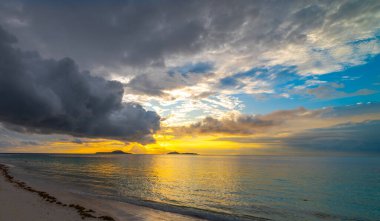 Alacakaranlıkta tropik bir sahilde dramatik bir gökyüzü. Praslin Adası, Seyşeller