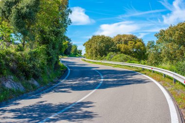 Güneşli bir günde dolambaçlı bir kır yolu. Sardunya, İtalya