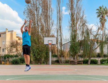 Basketbolcu dışarıda basket antrenmanı yapıyor.