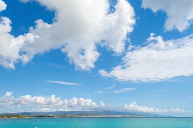 Mavi gökyüzünün altında büyük bulutlu turkuaz deniz.