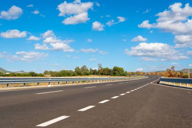 Bulutlu mavi gökyüzünün altındaki köy yolu