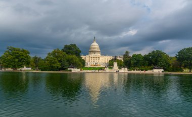 Birleşik Devletler Kongre Binası havuza yansıyan bulutlu bir gökyüzü altında. Washington D.C., ABD