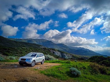 Araba bulutlu bir gökyüzünün altında kırsal alanda park edilmiş. Macera konsepti