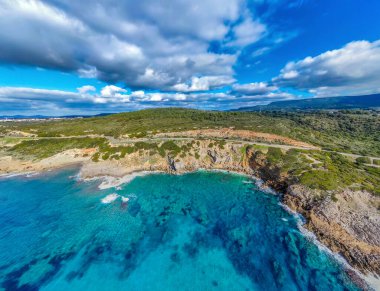Bulutlu bir gökyüzünün altındaki kayalık bir sahilin havadan görünüşü. Sardunya, İtalya