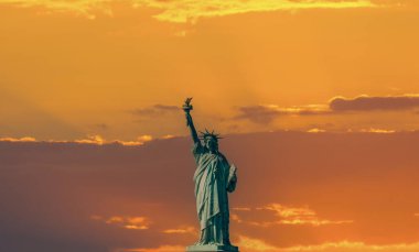 Dünyaca ünlü Özgürlük Heykeli gün batımında renkli bir gökyüzünün altında. New York City, ABD