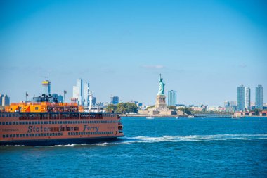 New York, ABD - Ekim 06, 2024: Güneşli bir sabahta dünyaca ünlü Özgürlük Heykeli 'nin yanından geçen Staten Island Feribotu