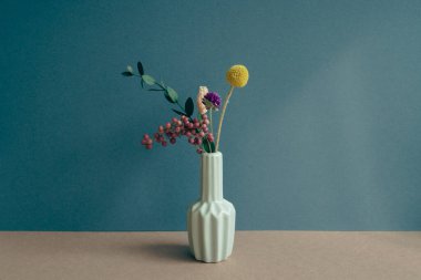 Masada bir vazo kuru çiçek var. Donanma mavi duvar arka planı. ev içi