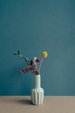 Masada bir vazo kuru çiçek var. Donanma mavi duvar arka planı. ev içi