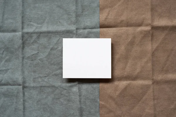 Blank memo pad on gray and brown fabric background. top view, copy space