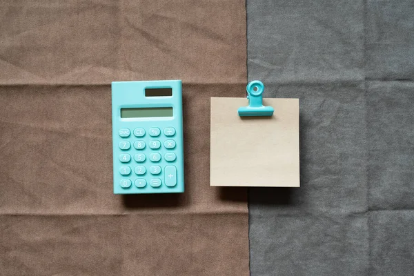 Mint calculator and memo pad on brown and gray fabric background. top view, copy space
