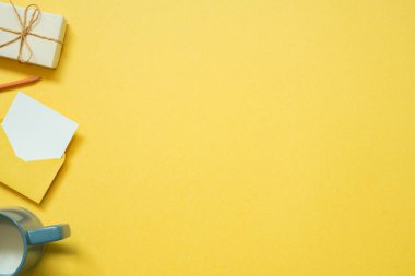 Gift box and envelope, cup of milk on yellow background. top view, copy space