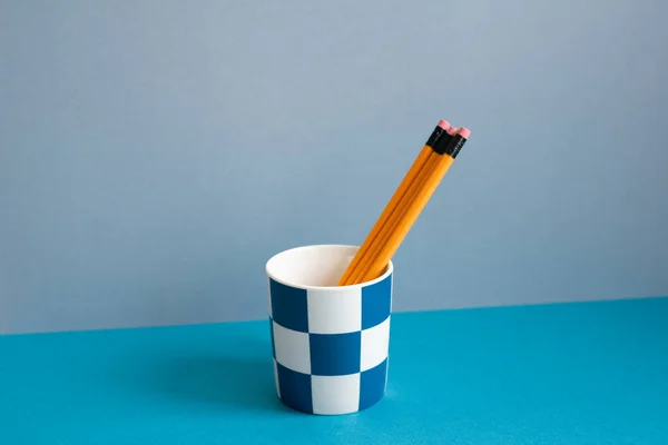 Yellow pencils in holder on blue desk