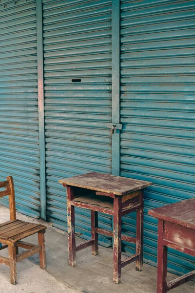 Abandoned wooden desk and chair in front of blue shutter door in Taiwan
