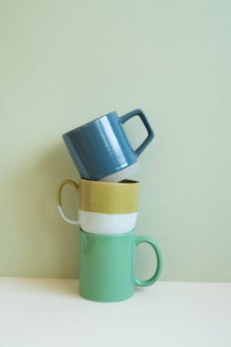 Mavi ve yeşil bardak yığını beyaz masada. Nane duvarlı arka plan. Boşluğu kopyala