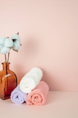 Banyo yumuşak temiz havlu ve pembe masa üzerinde pamuk çiçeği vazosu. Pembe duvar arka planı. Boşluğu kopyala