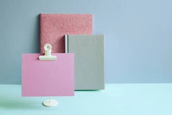 Pink notebook and memo pad on blue desk. blue wall background. workspace
