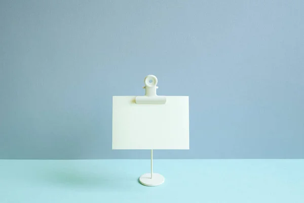 Blank memo pad and holder on blue desk. blue wall background