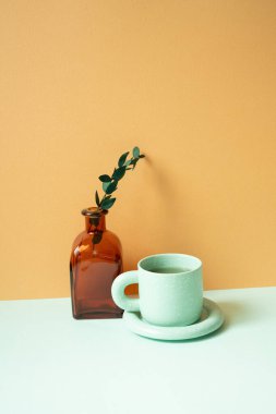 Nane yeşili masada bir fincan çay ve okaliptüs yaprağı. turuncu arkaplan