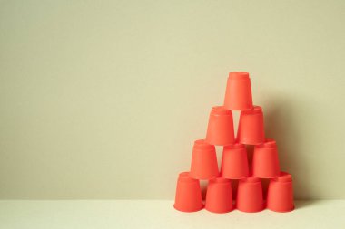 Masanın üzerinde kırmızı plastik bardaklar piramidi. haki bej arka plan. Takım çalışması denge işi başarı büyüme kavramını geliştirir