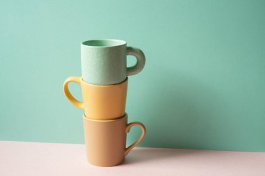 Kupa yığını pembe masanın üzerinde. nane yeşili duvar arkaplanı