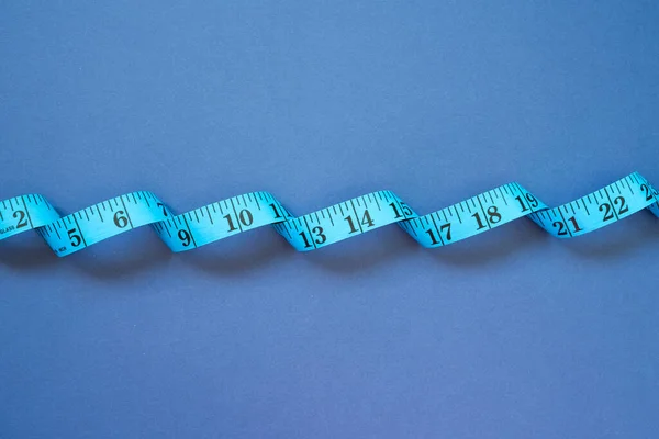 Tape measure on navy blue background. top view